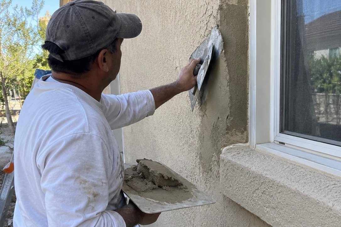 Stucco repair being completed on an exterior wall